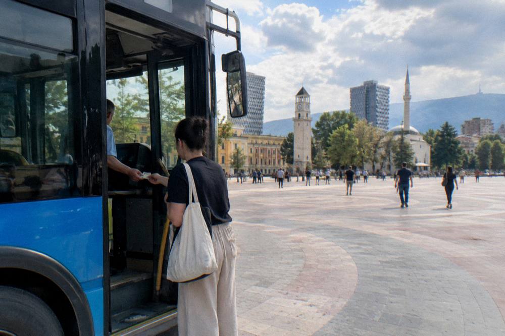 Passenger handing cash to a bus conductor on a Tirana city bus