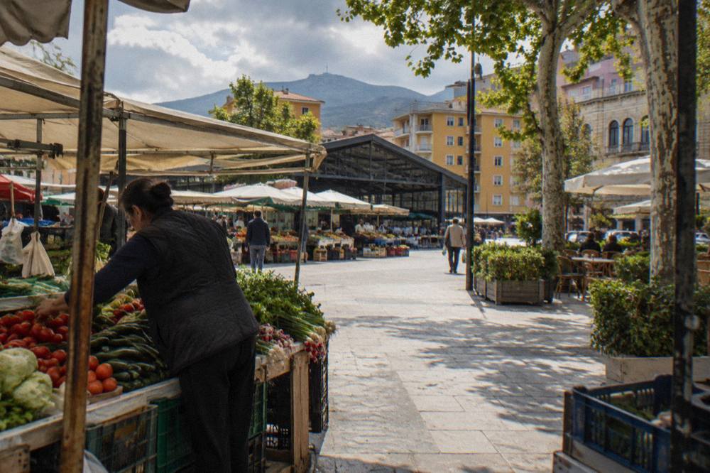 A market vendor arranging vegetables at a stall in the New Bazaar in Tirana