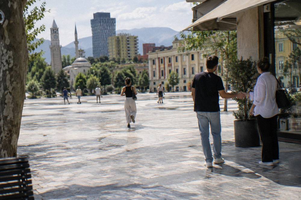 Two people shaking hands in greeting outside a shop in central Tirana