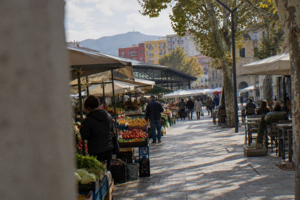 Shoppers and vendors talking across stalls at the New Bazaar in Tirana