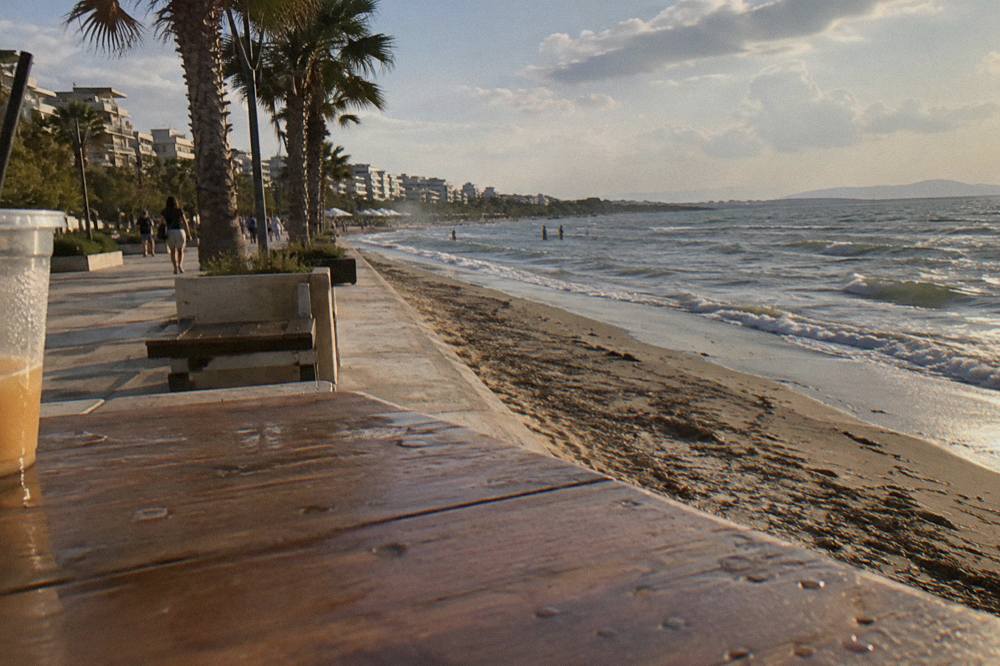 A promenade along a sandy beach lined with palm trees and apartment blocks