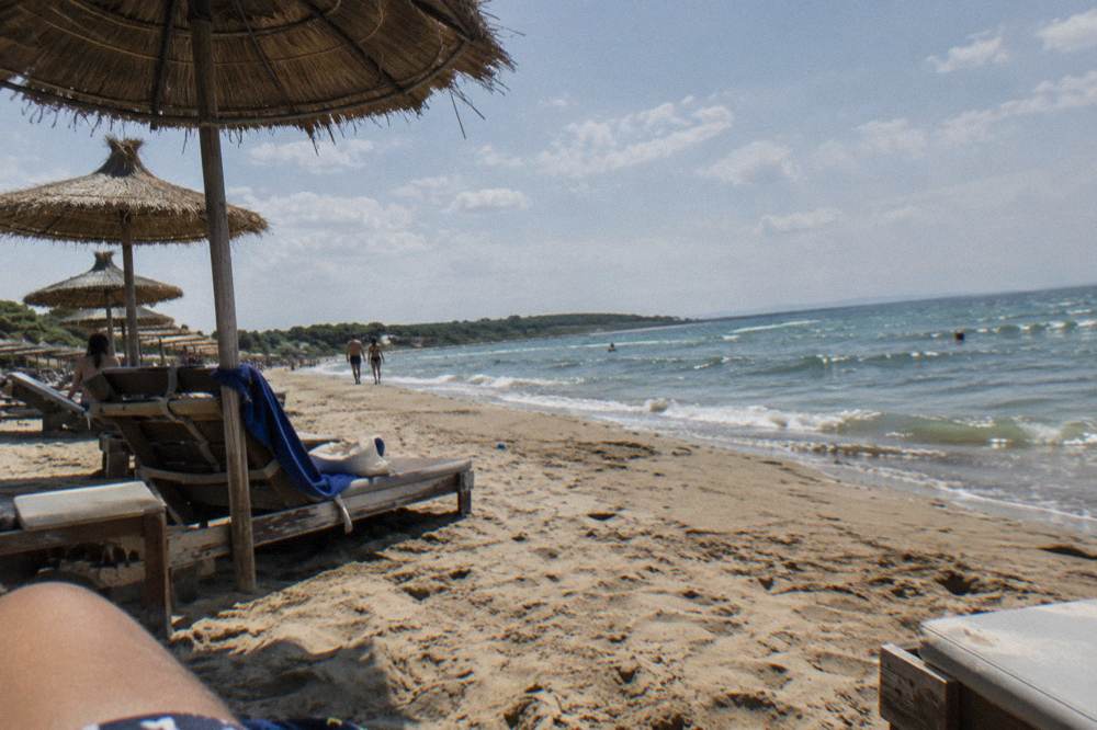 Sun loungers and parasols on golden sand beside gentle turquoise water