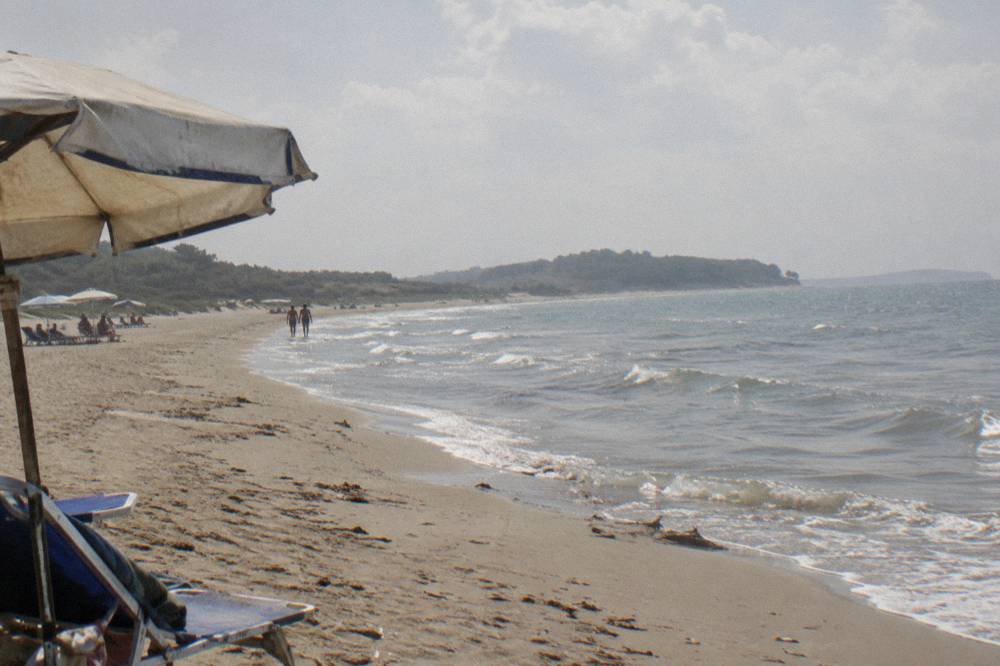 A long empty sandy beach curving toward a low green headland under a wide sky