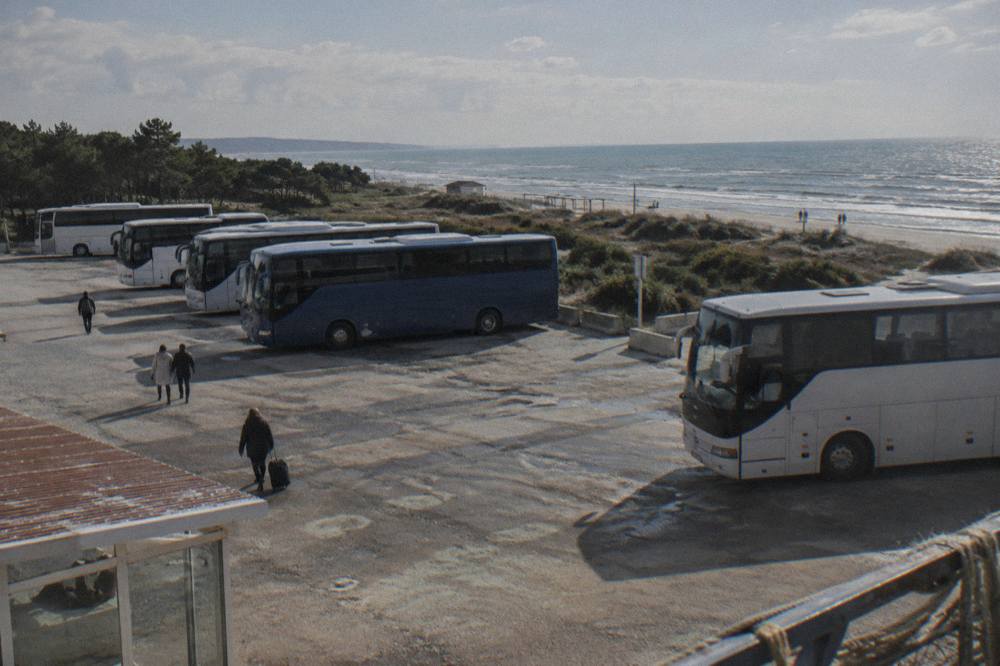 A bus terminal with coaches parked in a row under a bright sky