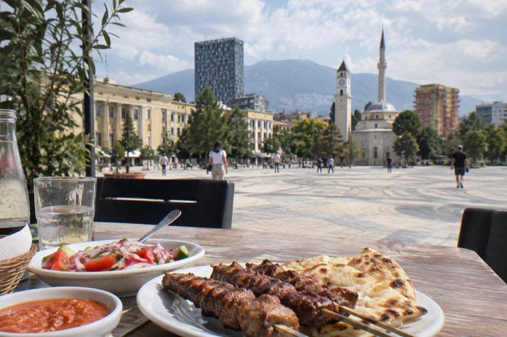 A table with grilled meat skewers, salad and flatbread at a Tirana restaurant