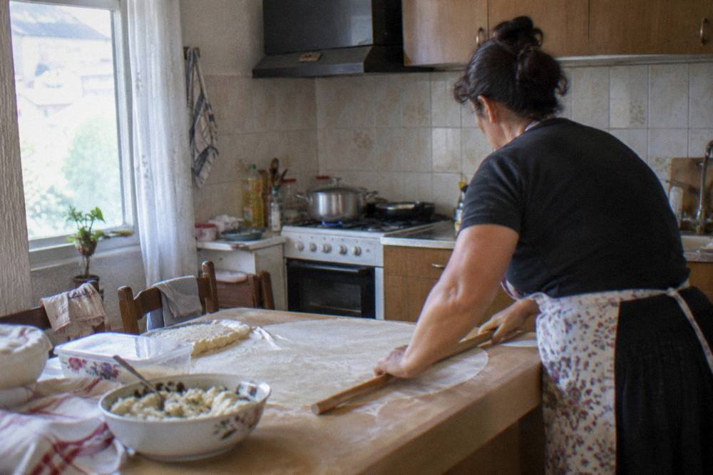 A cook rolling thin pastry dough for a pie in a home kitchen