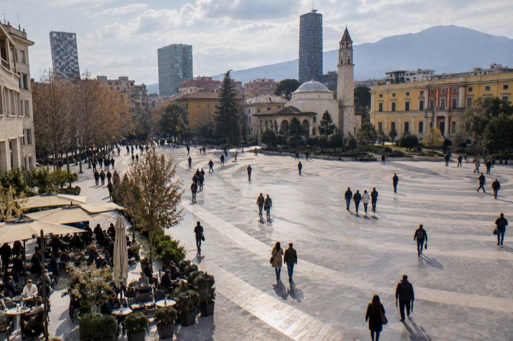 A busy pedestrian street with restaurant tables in central Tirana at lunchtime