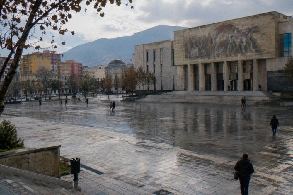 Wet pavement outside the National History Museum facade on Skanderbeg Square in Tirana