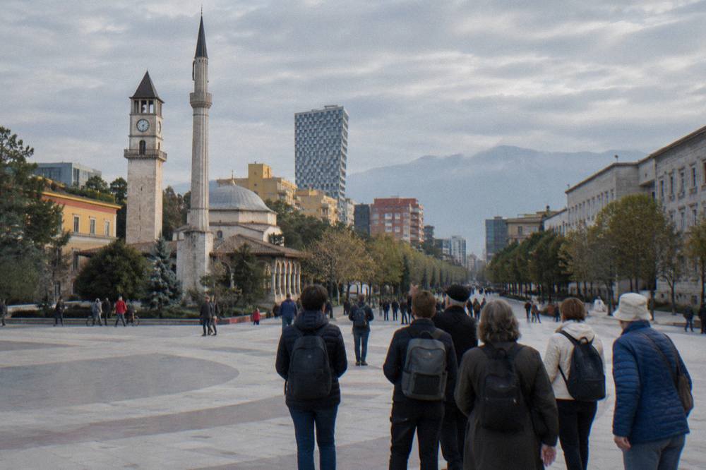 A guided walking group pausing on a pedestrian street in central Tirana