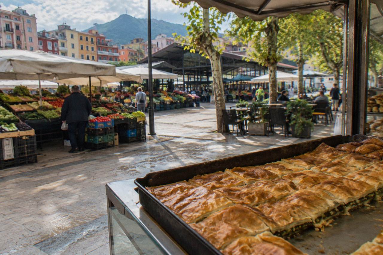 A freshly baked tray of golden filo pie cut into squares on a bakery counter