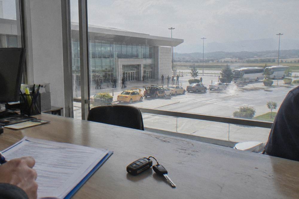 A rental agreement and car keys on a desk at a hire office counter