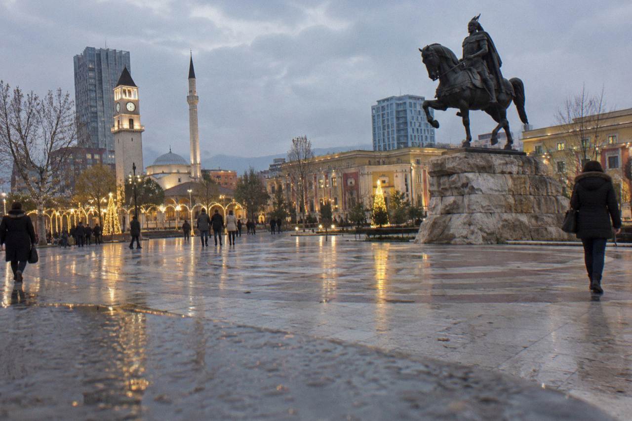 Skanderbeg Square in Tirana with holiday lights and the equestrian statue at dusk