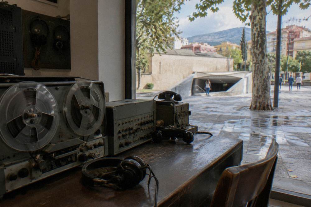 Vintage wiretapping receivers and reel recorders on a desk in a small museum room