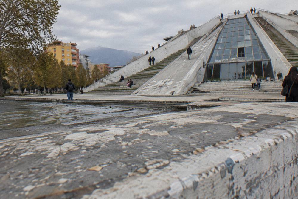 Stepped concrete pyramid building in a city park with people on the slopes