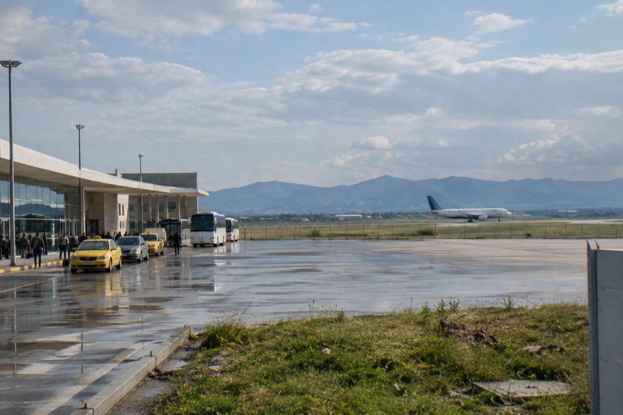 A passenger aircraft on the runway at Tirana International Airport with hills behind it