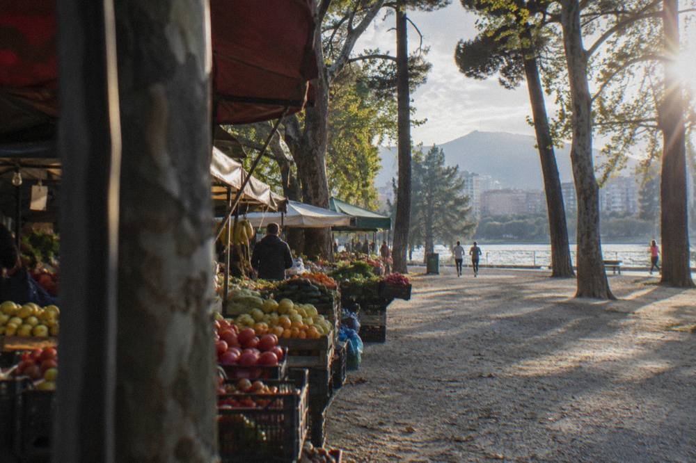 A market street with colourful produce stalls and awnings in a Balkan capital