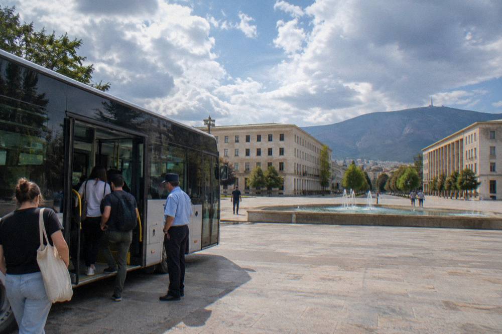 Passengers stepping onto a city bus while the conductor waits at the door