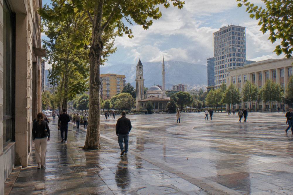 Boulevard in central Tirana with pedestrians walking past facades and plane trees