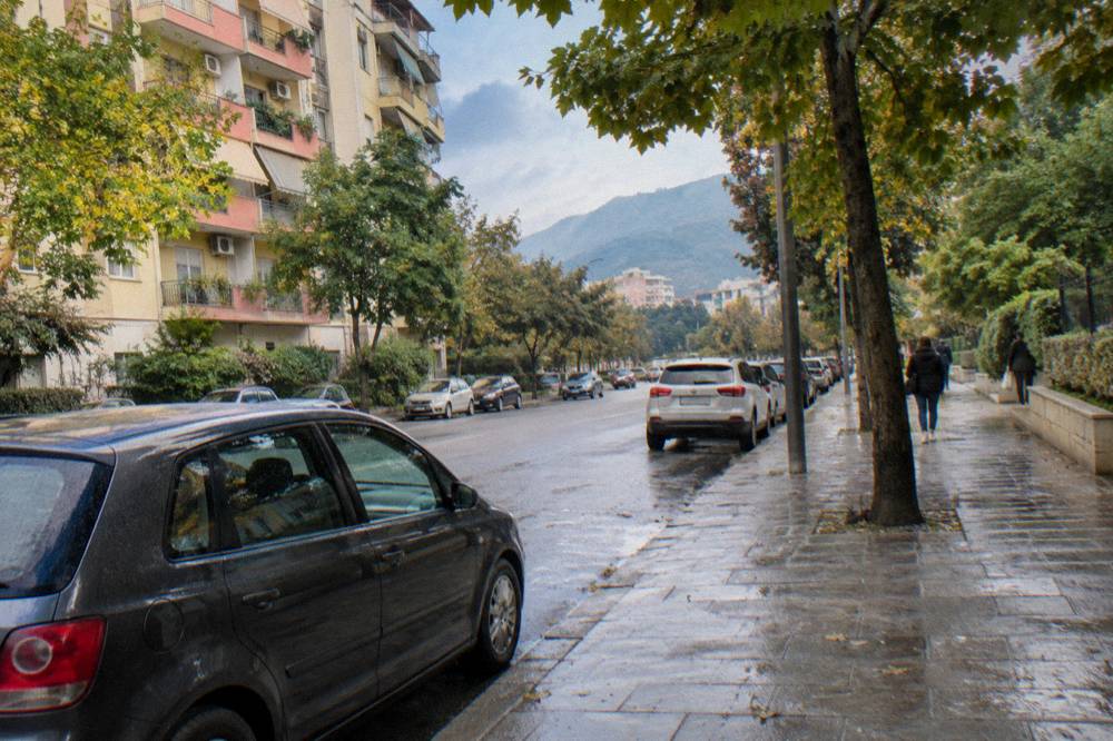 Leafy residential street with apartment blocks and parked cars in central Tirana