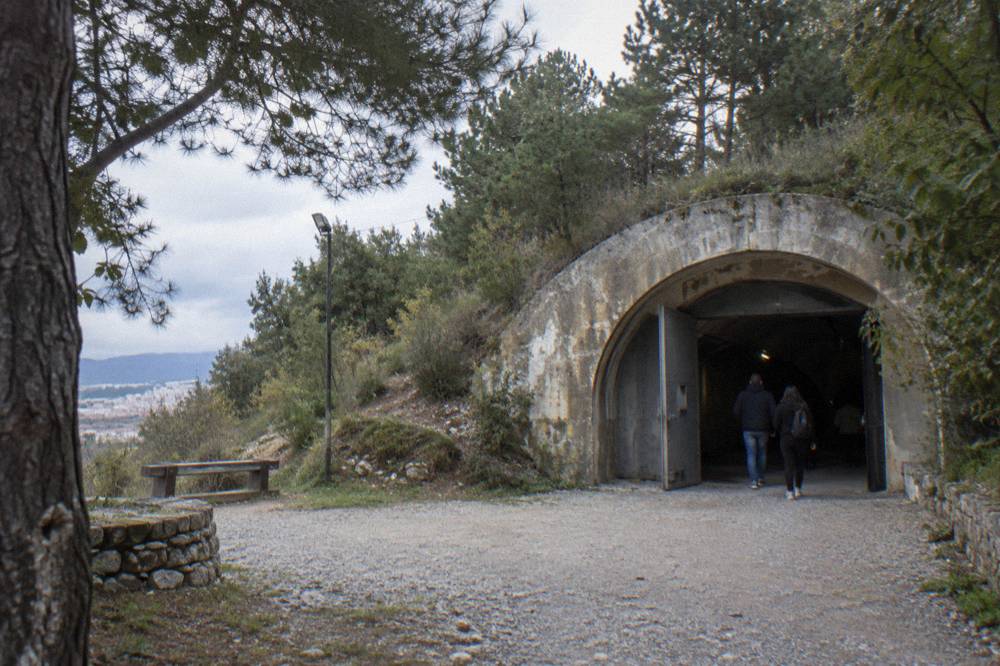 Visitors reading exhibits inside a dimly lit concrete bunker museum in Tirana