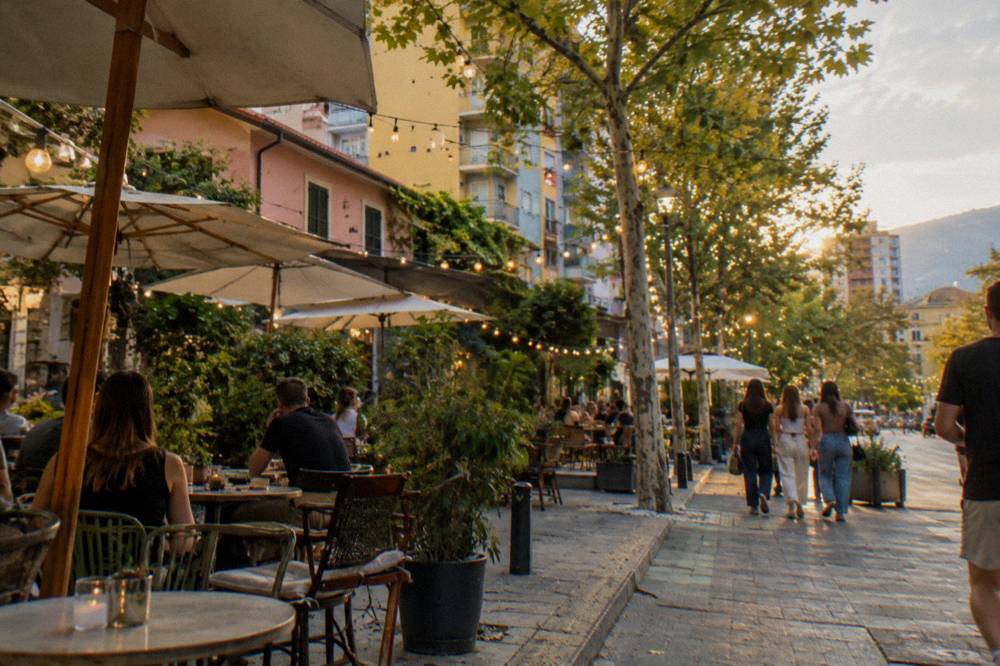 Cafe tables and string lights on an evening street in the Blloku quarter of Tirana