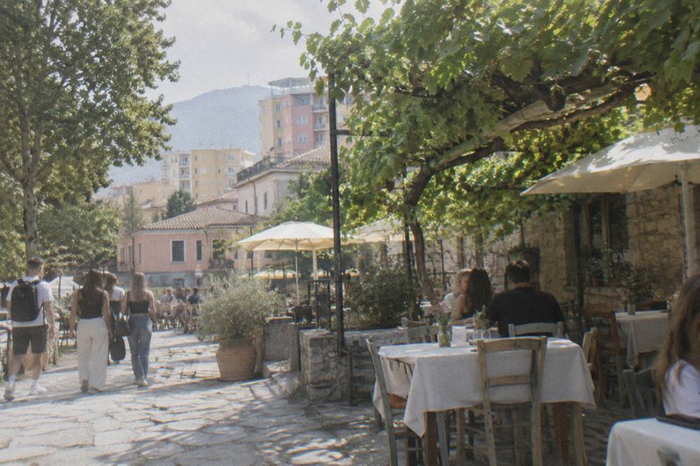 A stone courtyard restaurant with linen tables under vines in a southern Albanian town