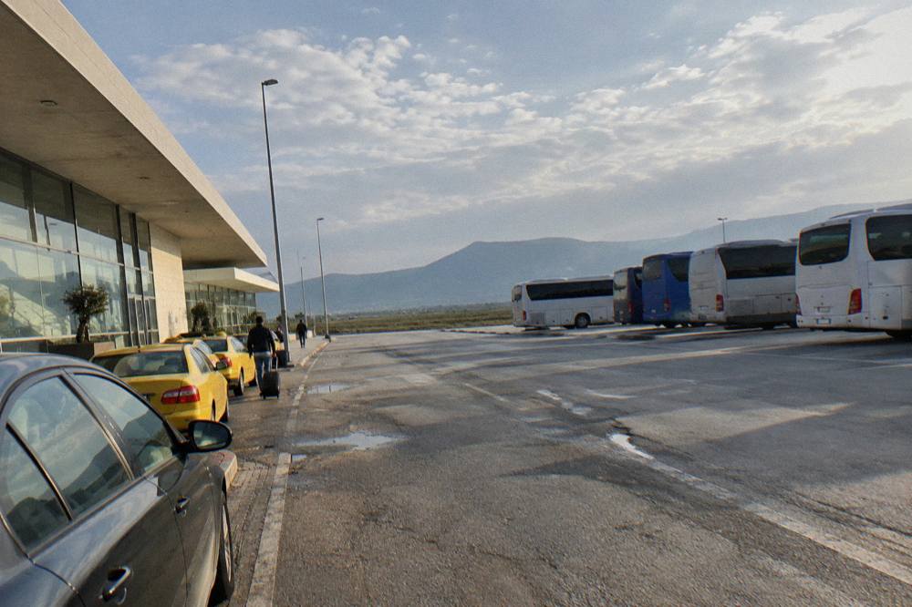 A row of regional coaches parked at a bus terminal with mountains in the distance