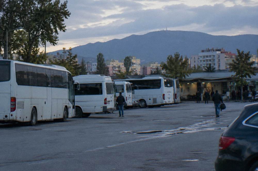 A timetable board at a bus terminal with departure times and Albanian city names