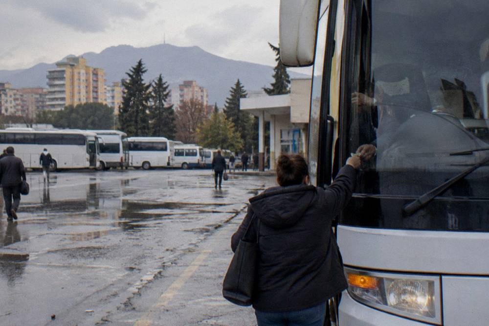 A passenger handing cash to a bus driver at the front of a coach