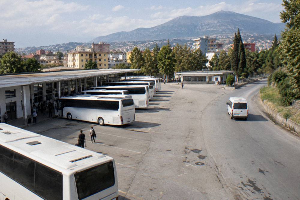 A minibus on a winding road heading towards mountains in Albania