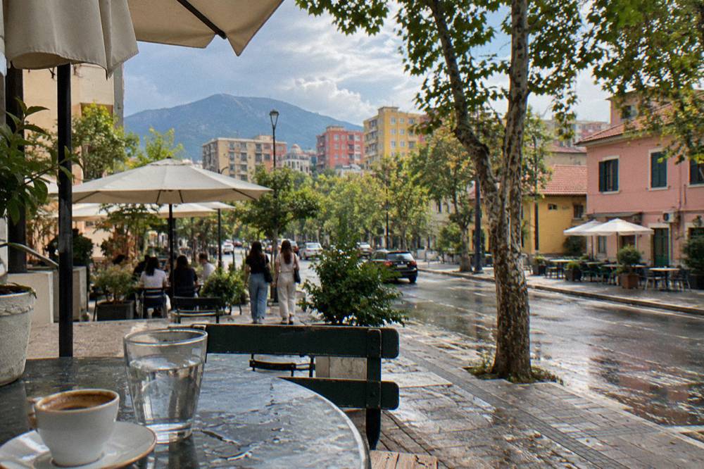A small cup of Turkish-style Albanian coffee beside a glass of water on a cafe table