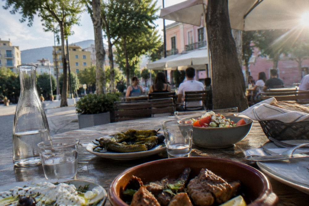 A spread of Albanian dishes and glasses of raki on a wooden table ready for a meal