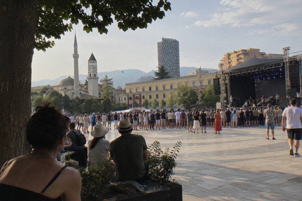 An open-air concert crowd in a city square on a summer evening