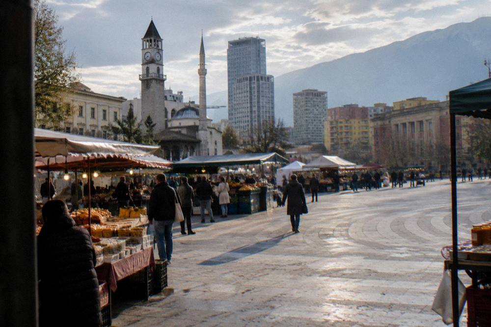 People browsing food stalls at an evening market in Tirana