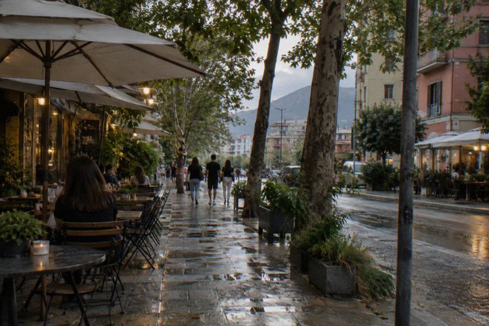 Cafe tables and trees on an evening street in the Blloku district of Tirana