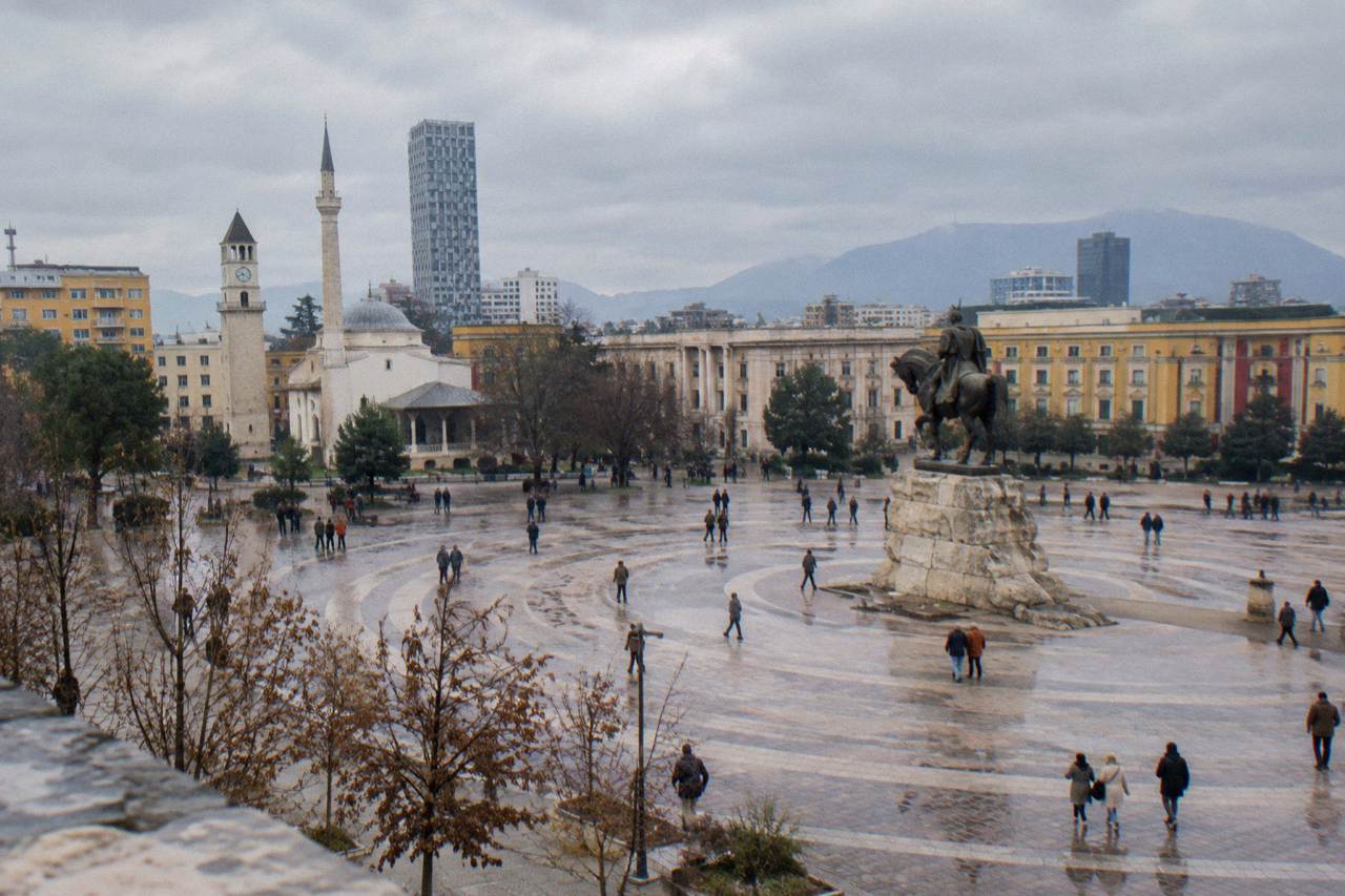 Skanderbeg Square in Tirana under a pale winter sky with the equestrian statue and ministry facades