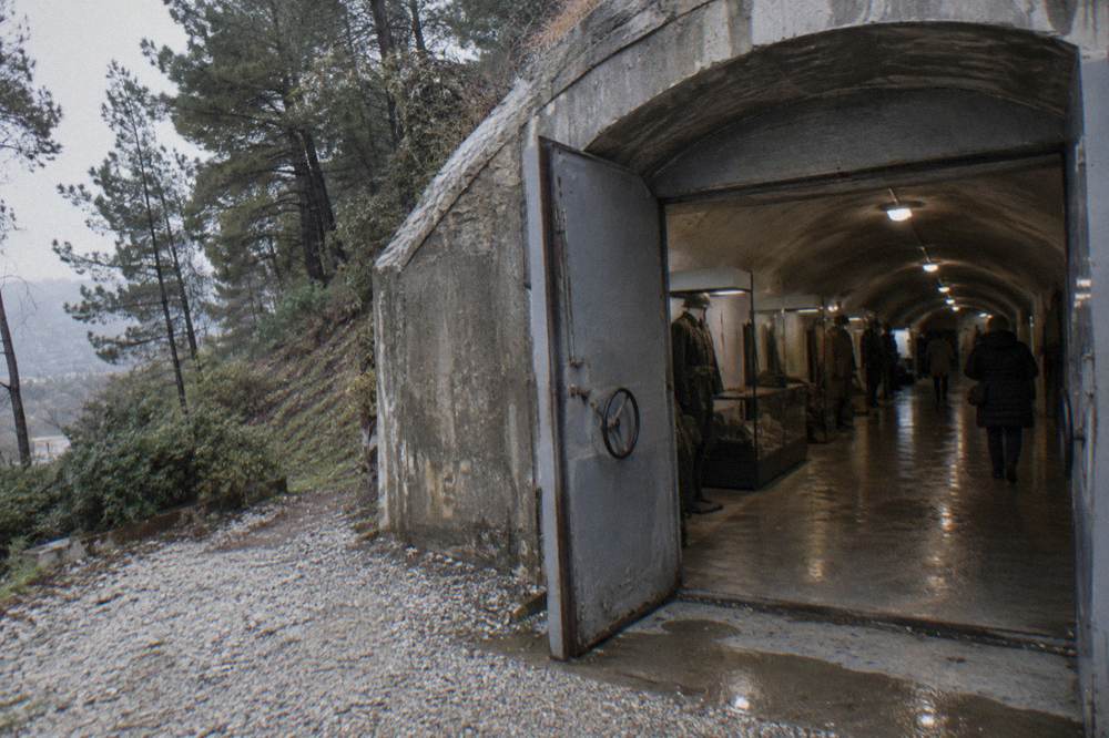 Interior corridor of a preserved communist-era bunker museum with exhibited uniforms and equipment