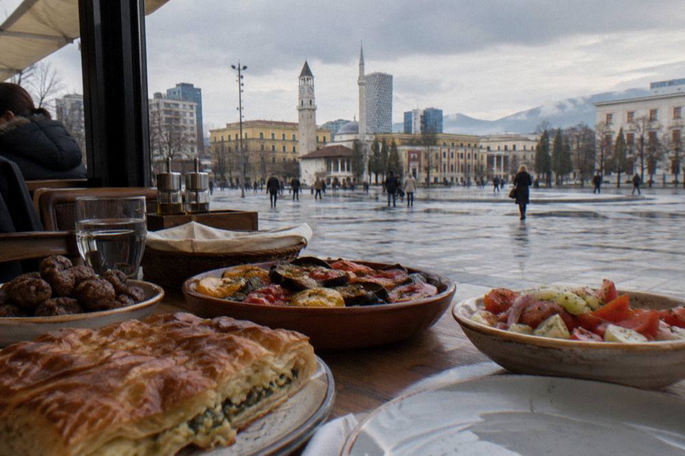 A packed table of Albanian winter dishes, byrek, qofte and baked vegetables, in a warm Tirana restaurant