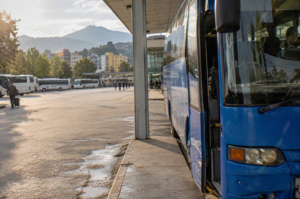 A blue airport shuttle bus parked at a kerb outside a modern terminal building