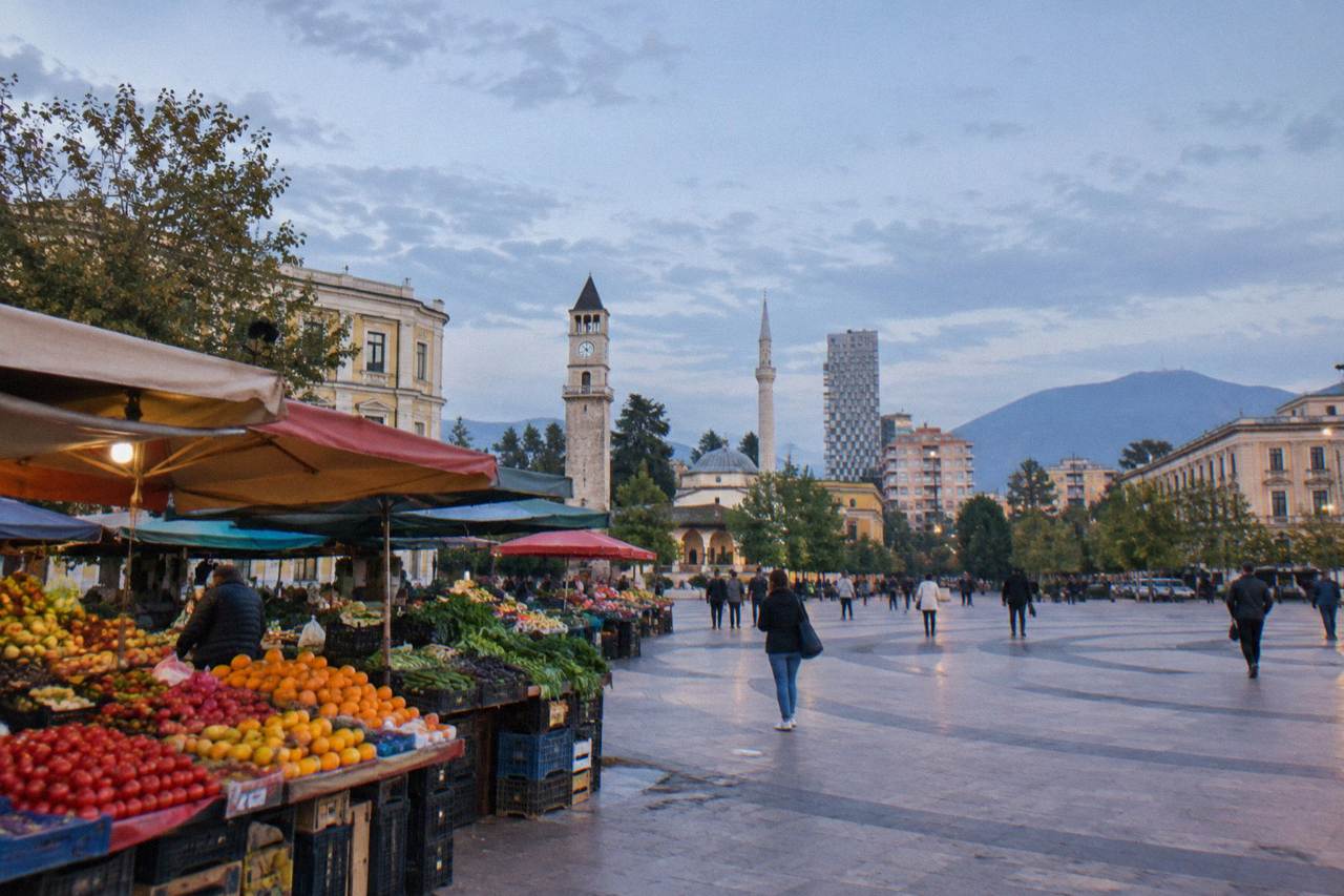 Colourful fruit and vegetable stalls under the awnings of a city market in Tirana