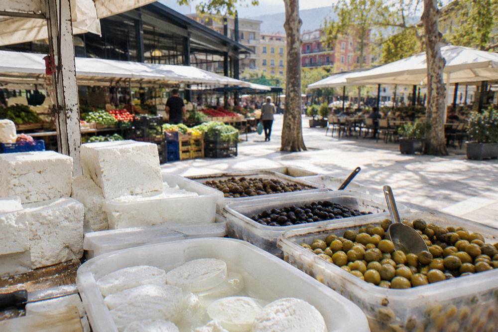 A close view of a cheese and olive counter with containers of white cheese and olives