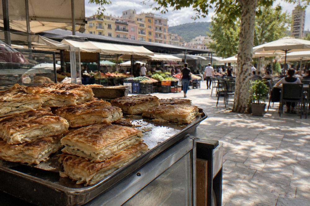 A tray of freshly baked layered pies stacked at a bakery counter in a market