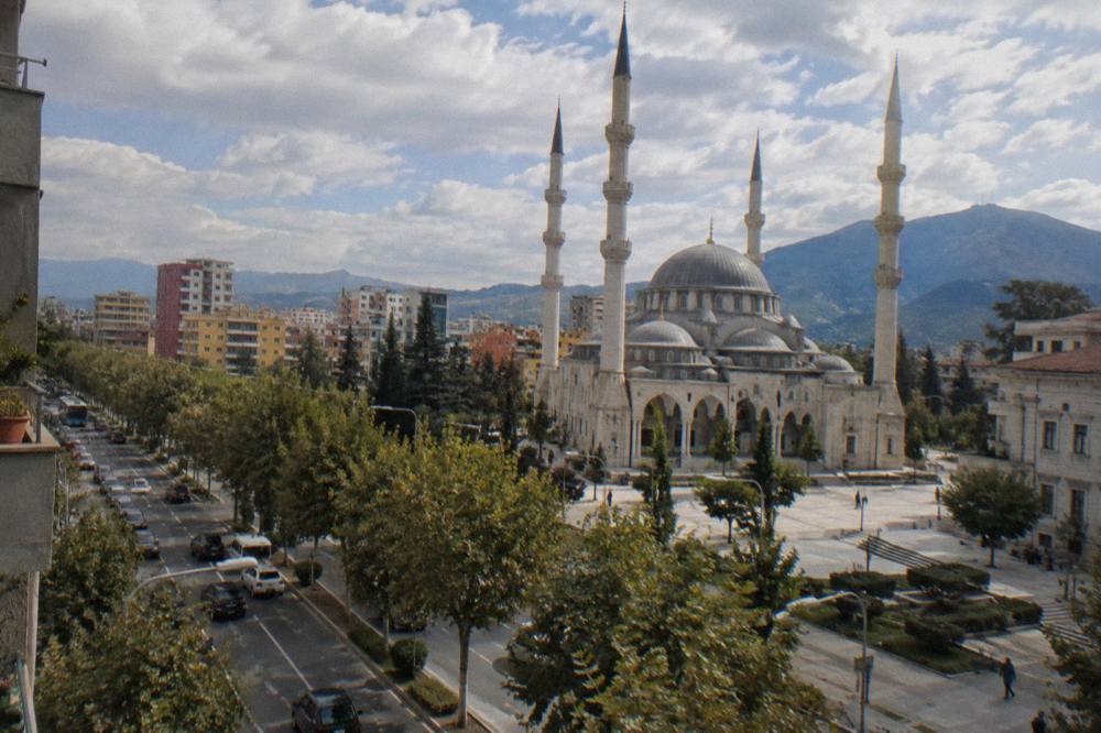 The dome and minarets of the Great Mosque of Tirana seen from a city street