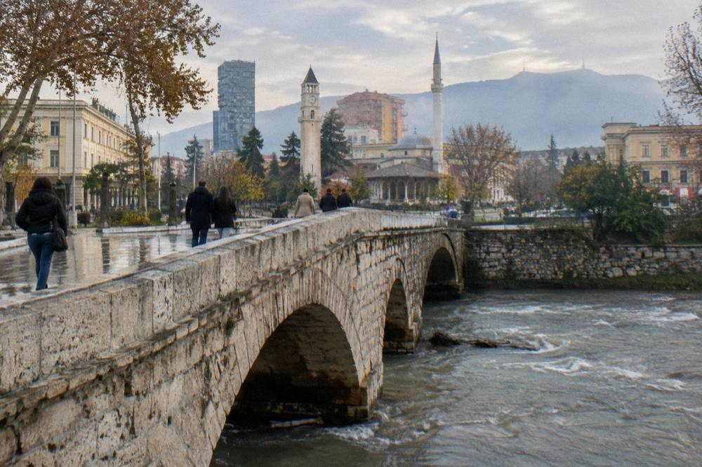 An Ottoman stone bridge on a Tirana street with pedestrians crossing