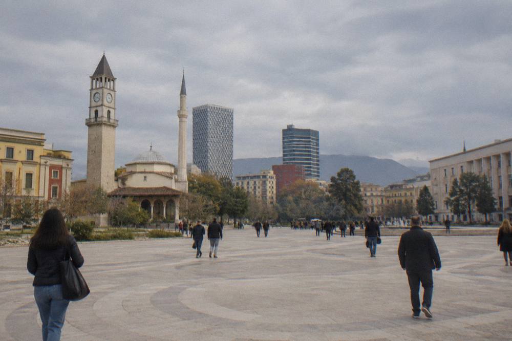 A museum gallery hall with high ceilings and visitors looking at paintings in Tirana