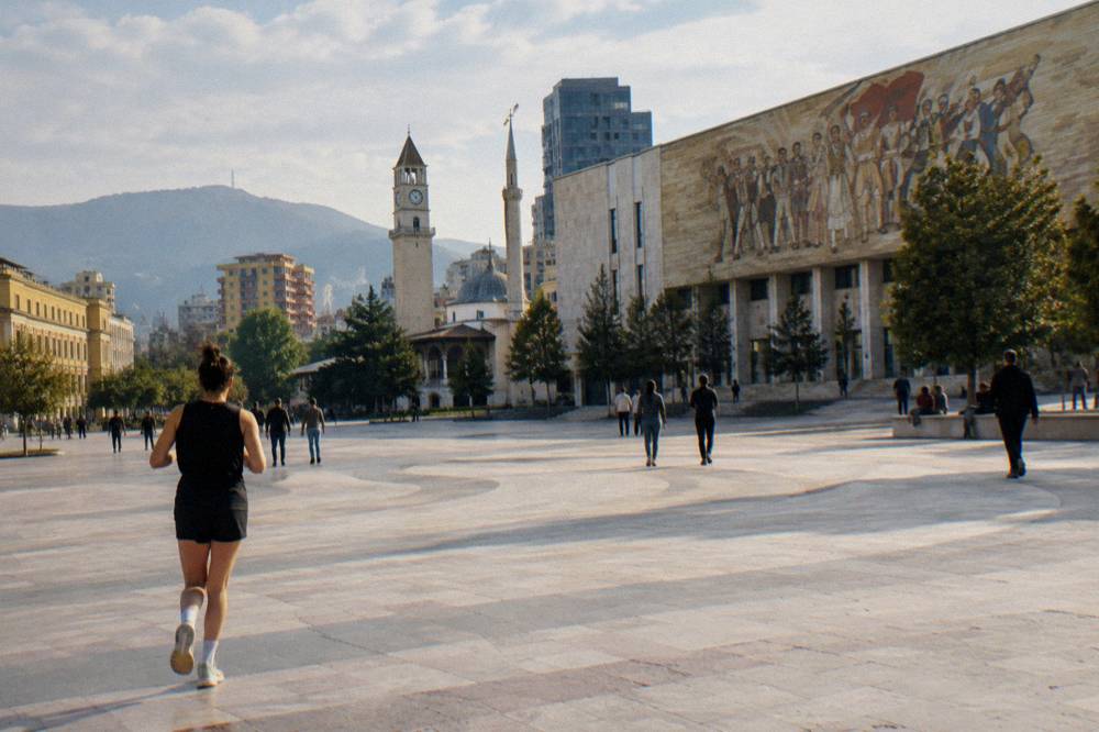 The mosaic facade of a large museum building above a pedestrian square in Tirana