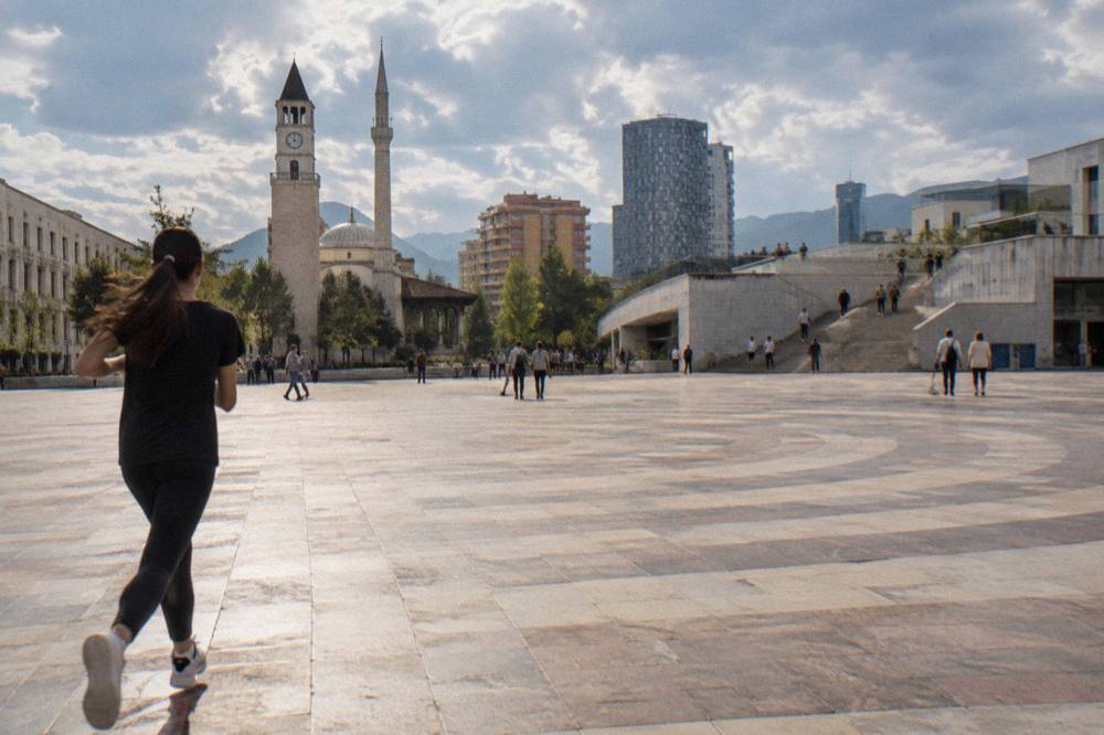 A stepped modern structure with people climbing an exterior staircase in central Tirana