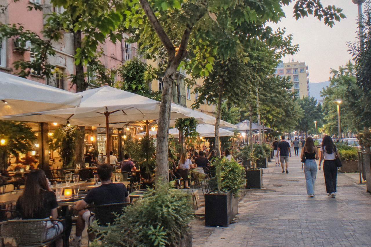 Illuminated cafe and bar terraces on a tree-lined street in the Blloku quarter of Tirana at night