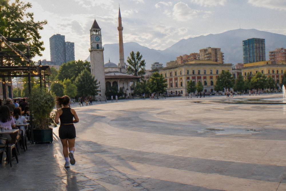 People seated at outdoor tables under string lights on a pedestrian street in central Tirana in the evening