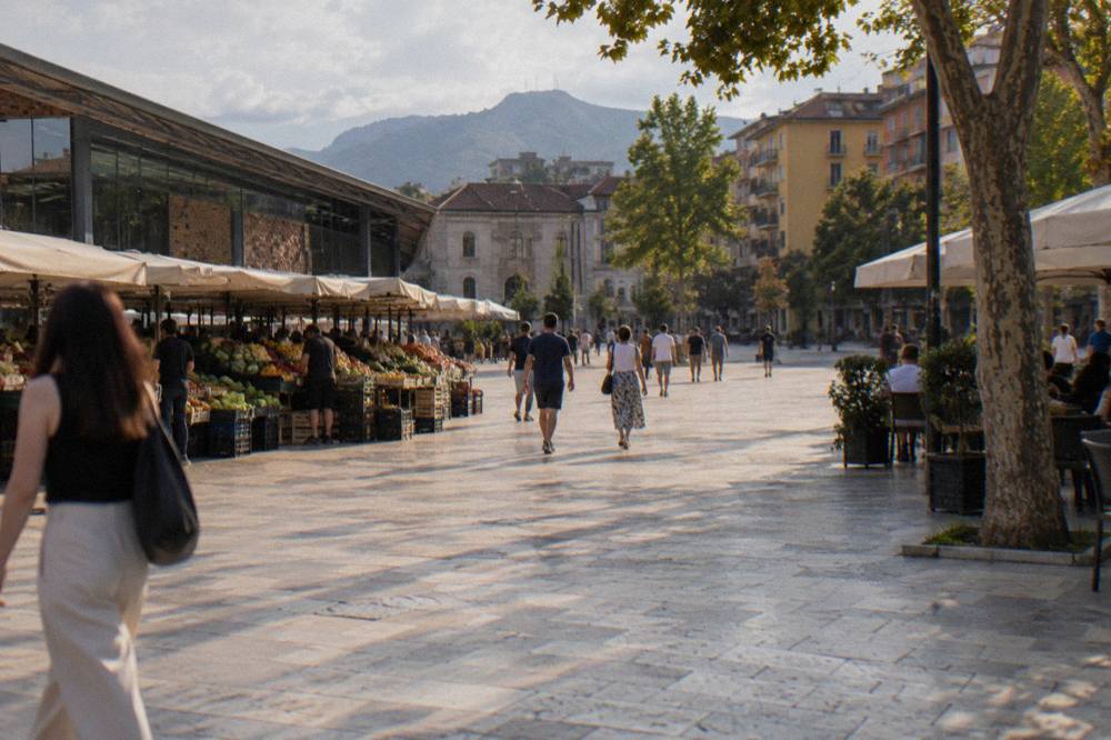 People crossing the open stone expanse of Skanderbeg Square on a bright day